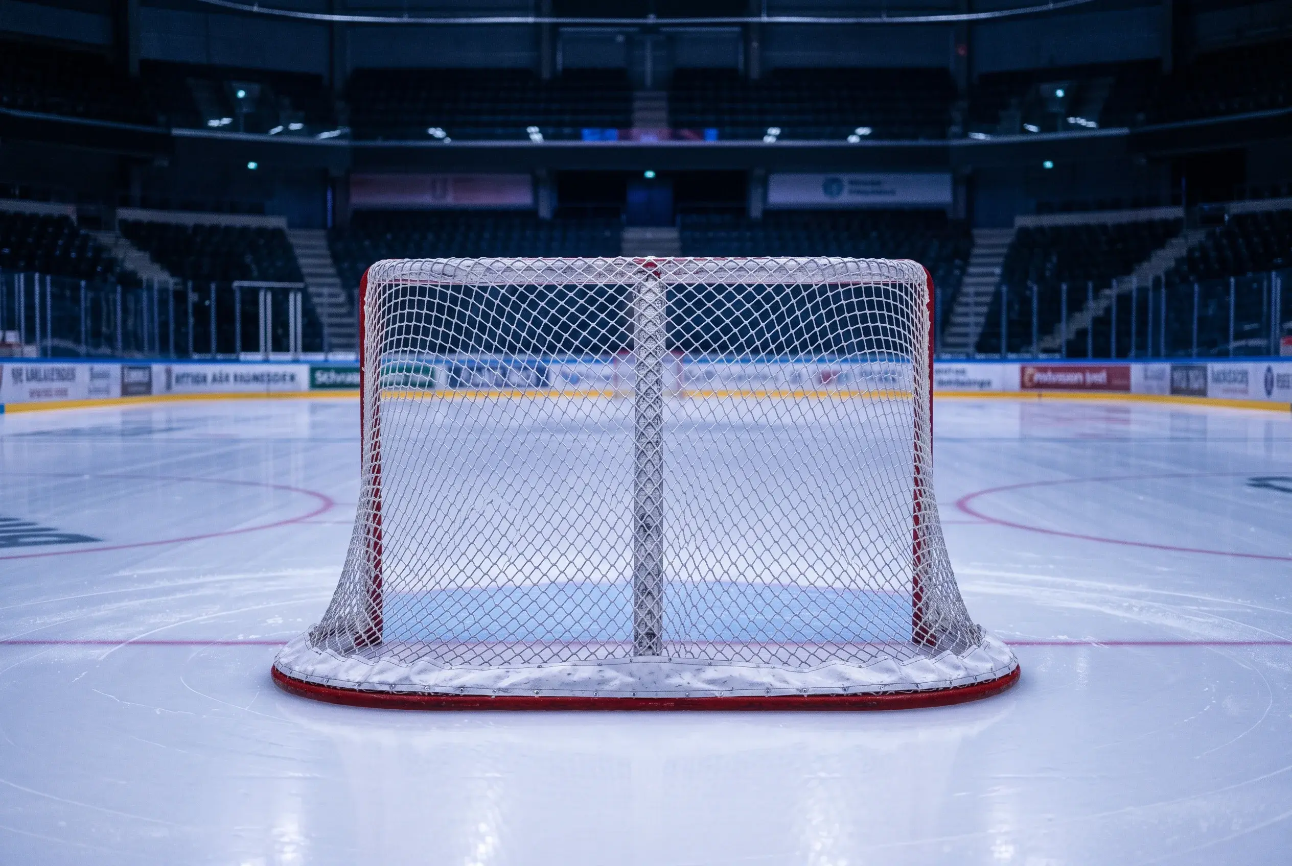 Ishockey-mal med net set forfra pa en tom isbane med blat lys