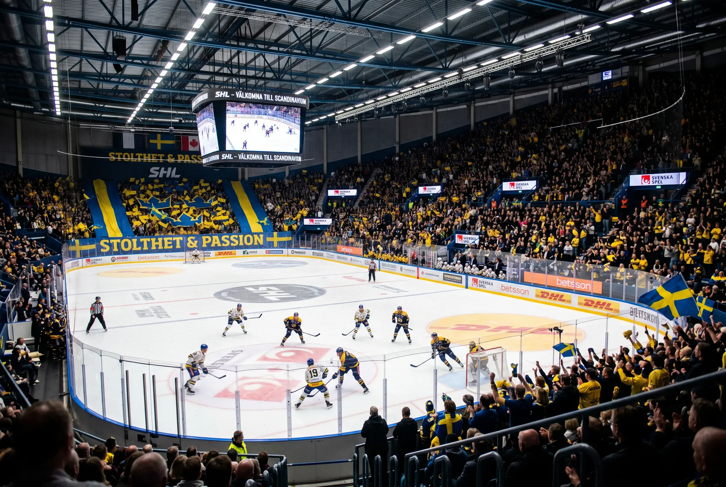 Svensk ishockey-arena med spillere pa isen og fyldte tribuner